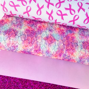 May include: Four sheets of fabric in various shades of pink. The top sheet features a white background with a repeating pattern of pink ribbons. The second sheet is a pink and purple tie-dye pattern. The third sheet is a solid light pink. The bottom sheet is a sparkly pink glitter fabric.
