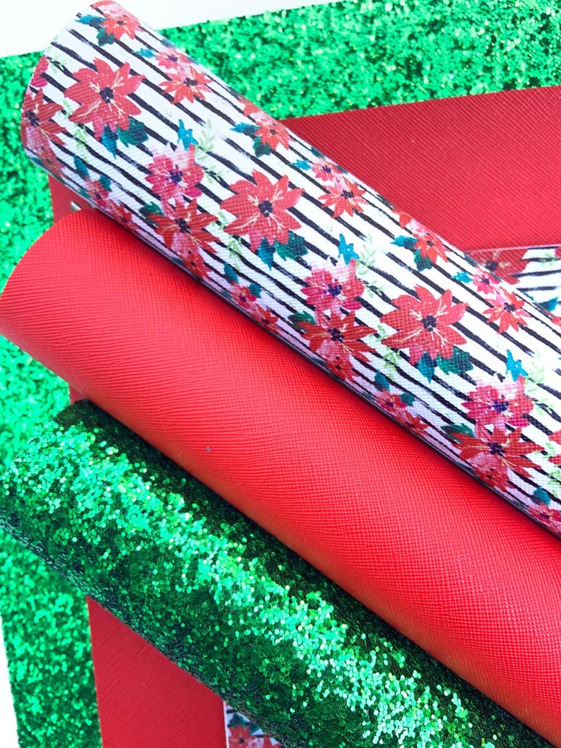 May include: A set of three fabric sheets in red, green, and white. The white sheet has a black and white striped pattern with red poinsettia flowers. The red sheet is a solid color. The green sheet is a sparkly glitter fabric.