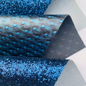 Op de afbeelding: Drie verschillende blauwe stofstalen. De bovenste staal is een glinsterende blauwe stof. De middelste staal is een blauwe stof met een textuurpatroon van kleine cirkels. De onderste staal is een glinsterende blauwe stof.