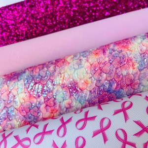 May include: A stack of four different pink patterned fabrics. The top fabric is a sparkly pink glitter fabric. The second fabric is a solid light pink. The third fabric is a pink and white tie-dye fabric with a heart pattern. The bottom fabric is white with a pink ribbon pattern.