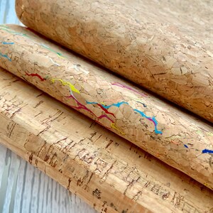 May include: Three sheets of cork fabric with different patterns. The top sheet is plain, the middle sheet has colorful lines, and the bottom sheet has a more textured pattern.