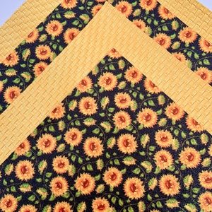May include: Three sheets of patterned craft paper. The top sheet is a yellow woven pattern. The middle sheet is a yellow woven pattern with a black border. The bottom sheet is a black background with a repeating pattern of yellow sunflowers.