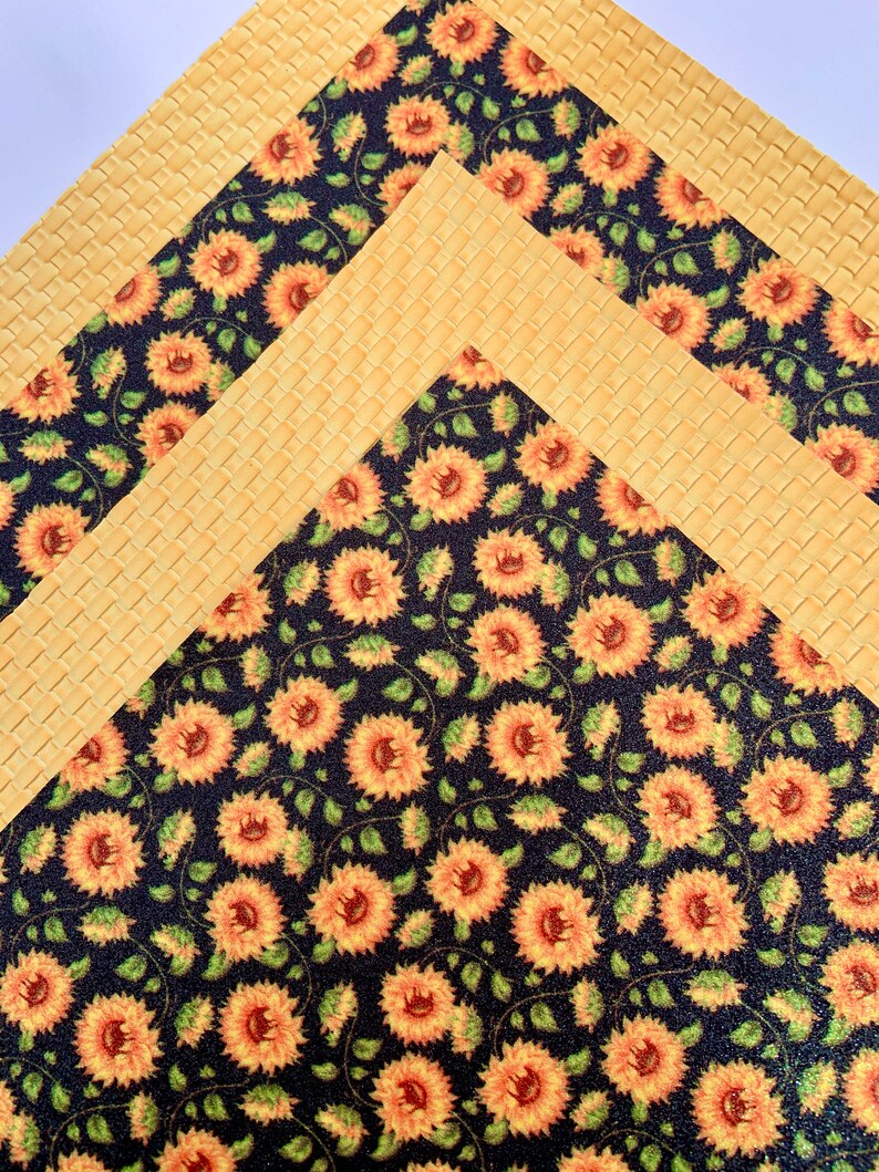 May include: Three sheets of patterned craft paper. The top sheet is a yellow woven pattern. The middle sheet is a yellow woven pattern with a black border. The bottom sheet is a black background with a repeating pattern of yellow sunflowers.