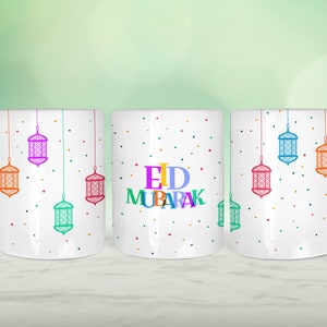 May include: Three white ceramic mugs with colourful Eid Mubarak text and hanging lanterns on a white background. The mugs have a white background with colourful polka dots.