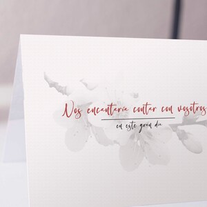 Op de afbeelding: Een witte kaart met een aquarel bloemenontwerp en de tekst "Nos encantar&iacute;a contar con vosotros en este gran d&iacute;a" in rood.