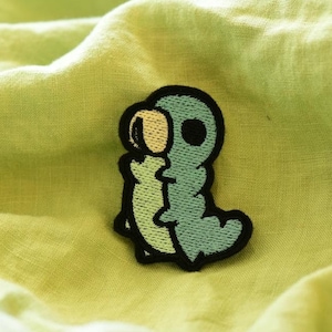 May include: An embroidered iron-on patch of a cartoon caterpillar, featuring green and yellow colours with black outlines.