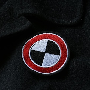 May include: A black and white circle with a red ring around it. The circle is divided into four quadrants, with each quadrant alternating between black and white.