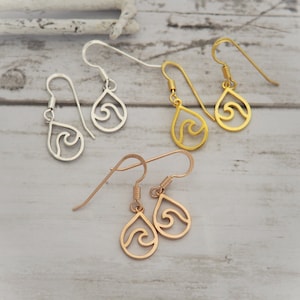 May include: Three pairs of dangle earrings with a wave design inside a teardrop shape. The earrings are silver, gold, and rose gold.