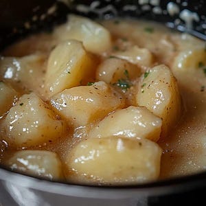 Può includere: Primo piano di una ciotola di purè di patate cremoso con una salsa marrone chiaro e erbe verdi.