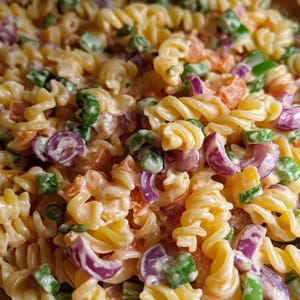 Puede incluir: Primer plano de una ensalada de pasta con cebolla roja, cebolla verde y zanahorias. La pasta está cubierta con un aderezo cremoso.