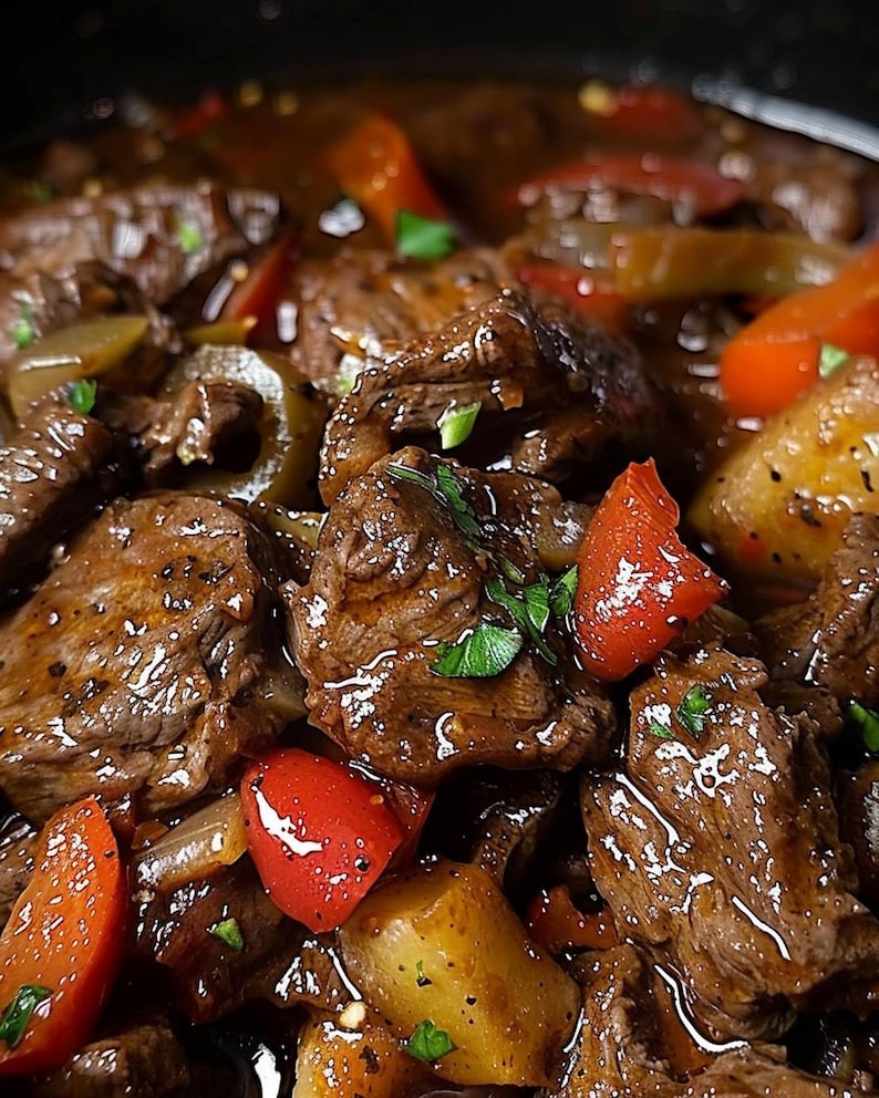 May include: A close-up shot of a rich beef stew, featuring tender pieces of meat, bright red bell peppers, and golden potatoes. The stew is sprinkled with fresh green herbs, presenting a delicious and appetizing meal.