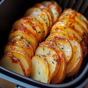 Puede incluir: Primer plano de un gran lote de rodajas de patata crujientes, cocinadas en una freidora de aire. Las patatas son de color marrón dorado y tienen una textura ligeramente crujiente. Las patatas están dispuestas en una sola capa en la cesta de la freidora de aire.
