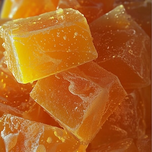 May include: Close-up of a pile of translucent, amber-colored, square-shaped candies. The candies have a slightly textured surface.