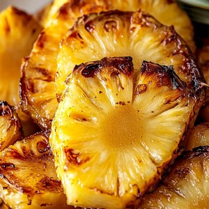Puede incluir: Primer plano de rodajas de piña asada. La piña es de color marrón dorado y caramelizada, con un exterior ligeramente carbonizado. Las rodajas están dispuestas en una pila, mostrando el interior jugoso y dulce.