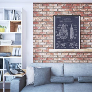 Pode incluir: Uma ilustra&ccedil;&atilde;o em preto e branco de um machado de m&atilde;o, tamb&eacute;m conhecido como machado de punho, sobre um fundo azul escuro. A ilustra&ccedil;&atilde;o inclui um diagrama das diferentes partes do machado e uma descri&ccedil;&atilde;o de seu uso. A ilustra&ccedil;&atilde;o est&aacute; emoldurada e pendurada em uma parede de tijolos acima de um sof&aacute; cinza.