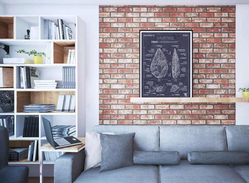 Pode incluir: Uma ilustra&ccedil;&atilde;o em preto e branco de um machado de m&atilde;o, tamb&eacute;m conhecido como machado de punho, sobre um fundo azul escuro. A ilustra&ccedil;&atilde;o inclui um diagrama das diferentes partes do machado e uma descri&ccedil;&atilde;o de seu uso. A ilustra&ccedil;&atilde;o est&aacute; emoldurada e pendurada em uma parede de tijolos acima de um sof&aacute; cinza.