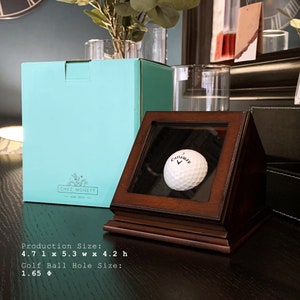 May include: A wooden display case with a glass front, showcasing a white golf ball with the Callaway logo. The case is 4.7 inches long, 5.3 inches wide, and 4.2 inches high. The golf ball hole size is 1.65 inches.