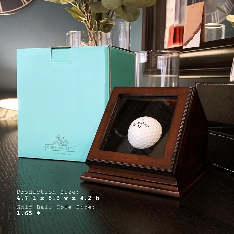 May include: A wooden display case with a glass front, showcasing a white golf ball with the Callaway logo. The case is 4.7 inches long, 5.3 inches wide, and 4.2 inches high. The golf ball hole size is 1.65 inches.
