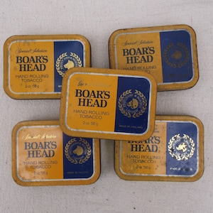 Può includere: Cinque barattoli di metallo gialli e blu di tabacco da rollare Boar's Head. Ogni barattolo ha un logo con la testa di cinghiale e il testo "Special Selection Boar's Head Hand Rolling Tobacco 2 oz 56g".