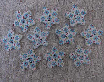 May include: Ten white wooden star-shaped buttons with a floral pattern in shades of blue, green, and red.