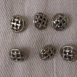 Peut inclure: Six boutons ronds en argent et or avec un motif tissé. Les boutons sont ronds et ont un motif en relief.