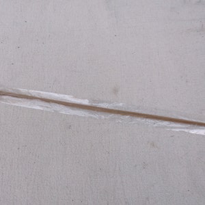 May include: A brown wooden knitting needle with a silver tip, wrapped in clear plastic.
