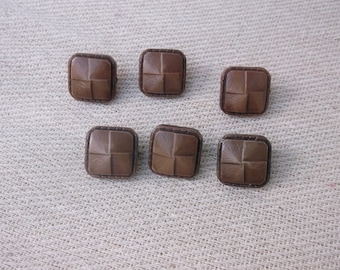 May include: Six brown square buttons with a woven pattern. The buttons have a raised design and a smooth finish.