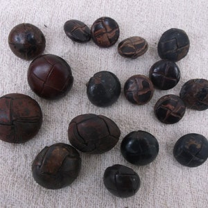 以下が含まれることがあります： ステッチデザインが施された茶色の革ボタン17個のセット。ボタンは様々なサイズと形をしています。