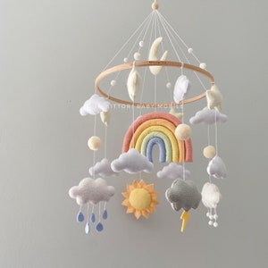 Cloud nursery mobile in pastel color palette with rainbow, sun, stars, rain cloud, snow. Weather baby mobile. Nursery decor with felt balls