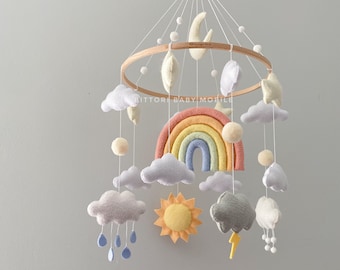 Cloud nursery mobile in pastel color palette with rainbow, sun, stars, rain cloud, snow. Weather baby mobile. Nursery decor with felt balls