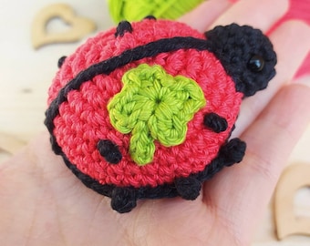 Mariquita amigurumi con trébol de cuatro hojas como llavero, tejida a crochet en algodón rojo y verde. Aprox. 6,5 cm de alto.