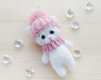Dulce y tierno gato blanco con ojos amarillos y azules, con gorro y bufanda rosas, de unos 14 cm de altura. Amuleto de la suerte.