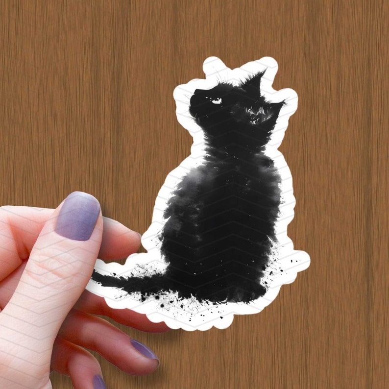 K&ouml;nnte beinhalten: Schwarz-wei&szlig;-Aquarell-Illustration einer Katze, die sitzt und zur Seite schaut. Die Katze ist wei&szlig; umrandet und hat einen Spritzeffekt um sich herum.