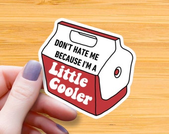 Op de afbeelding: Een rode en witte sticker met de tekst "Haat me niet omdat ik een beetje cooler ben" op een witte, koelboxvormige achtergrond.
