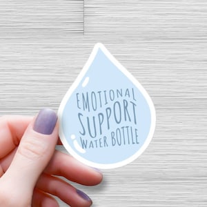 Peut inclure: Un autocollant en forme de goutte d'eau bleue avec le texte "Emotional Support Water Bottle" en blanc.