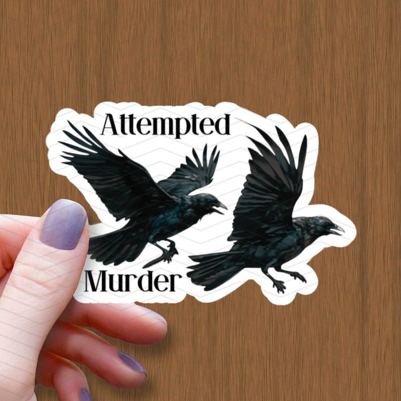 May include: A white sticker with two black crows flying. The sticker says "Attempted Murder" in black text.