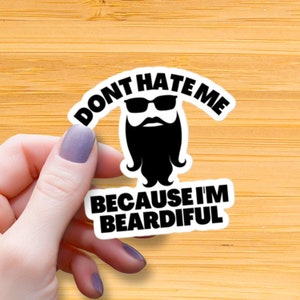 Puede incluir: Pegatina blanca con texto negro y una imagen de dibujos animados de un hombre barbudo con gafas de sol. El texto dice "Don't hate me because I'm Beardifull."