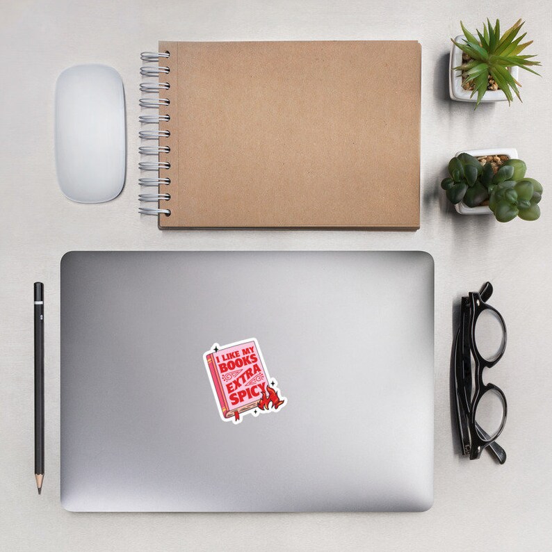 May include: A pink and red sticker with a book illustration and the text "I like my books extra spicy".