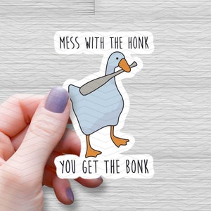 May include: A white sticker with a cartoon goose holding a baseball bat. The text on the sticker reads "Mess with the honk you get the bonk".