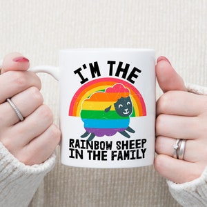 May include: White ceramic mug with a rainbow sheep design and the text "I'm the rainbow sheep in the family".