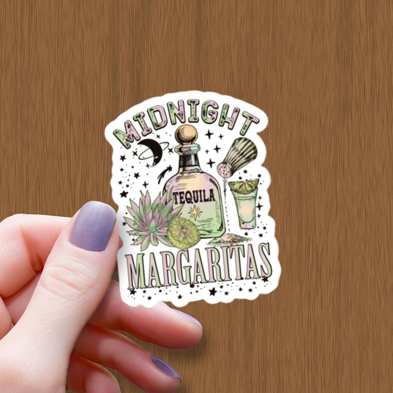 Op de afbeelding: Een witte sticker met een kleurrijke illustratie van een tequilafles, een zoutstrooier, een limoenwig en een margarita-glas. De tekst "MIDNIGHT MARGARITAS" is geschreven in een decoratief lettertype.