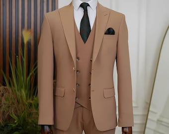 May include: A three-piece suit in a light brown color. The suit includes a jacket, vest, and pants. The jacket has a single-breasted closure and a notch lapel. The vest has a double-breasted closure and a V-neck. The pants have a flat front and a straight leg.
