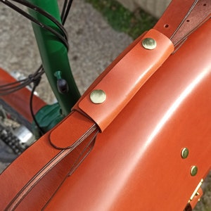 Bolso de cuero para bicicletas Brompton grande (para tablets,Macbook pro 13"...). Modelo de cuero marrón intermedio. Detalle del asa recogiendo la bandolera para cuando se monteen la bicicleta.