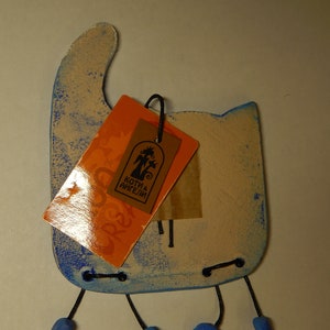May include: A blue and white ceramic cat figurine with a tag that reads "Koti & Angeli". The cat has three legs and blue feet.