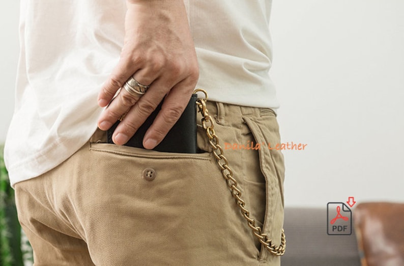 May include: A black leather wallet with a brass chain attached to it. The wallet is in the back pocket of a pair of khaki pants.