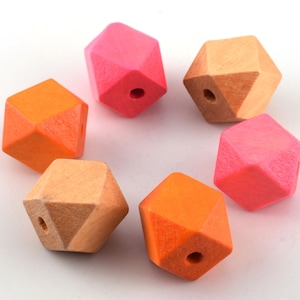 Może przedstawiać: Sześć drewnianych koralików o geometrycznym kształcie w kolorze różowym i pomarańczowym. Koraliki mają kształt diamentu z otworem w środku.
