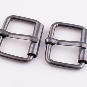 May include: Two silver metal belt buckles with a rectangular shape and a smooth finish.