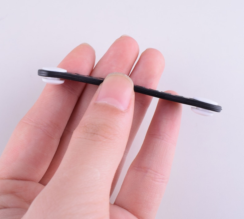 Puede incluir: Un organizador de cables negro con dos extremos de goma blanca. El organizador est&aacute; dise&ntilde;ado para mantener los cables ordenados y organizados.