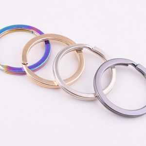May include: Four key rings in different colours: iridescent, gold, silver, and black. The key rings are all made of metal and are about 5 cm in diameter.