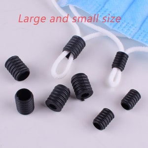 May include: A close-up of black plastic cord stoppers in various sizes. The stoppers are designed to secure cords and prevent them from fraying.  The text "Large and small size" is visible in the image.